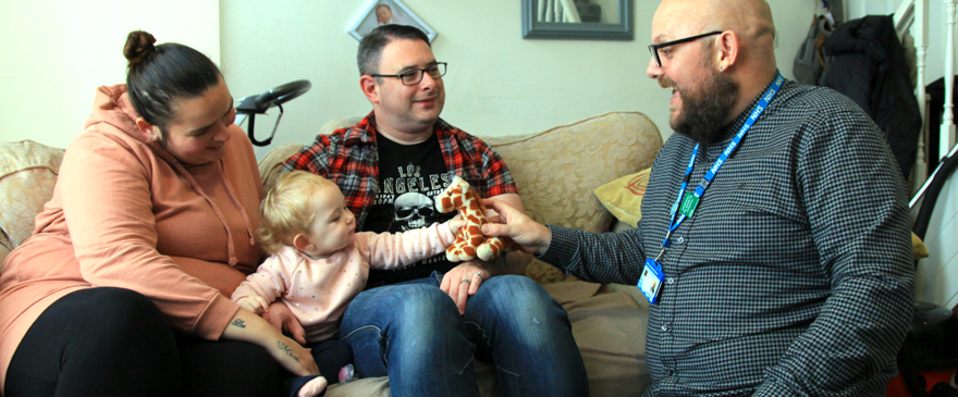 Male health visitor with mum, dad and toddler.