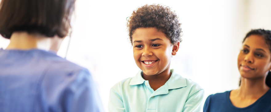 Child smiling with parent and health professional 